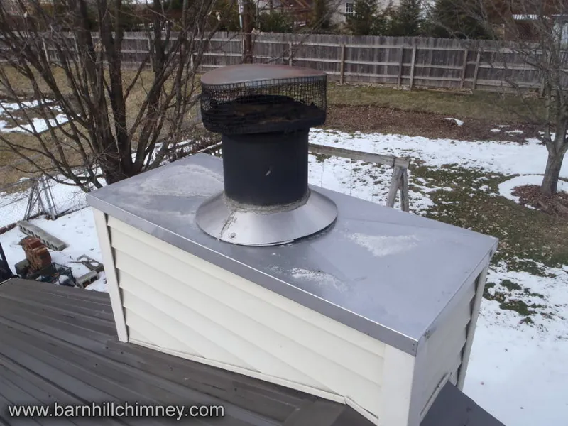 Warped metal chimney cap filled with chunks of fluffy creosote, evidence of a slow-burning chimney fire