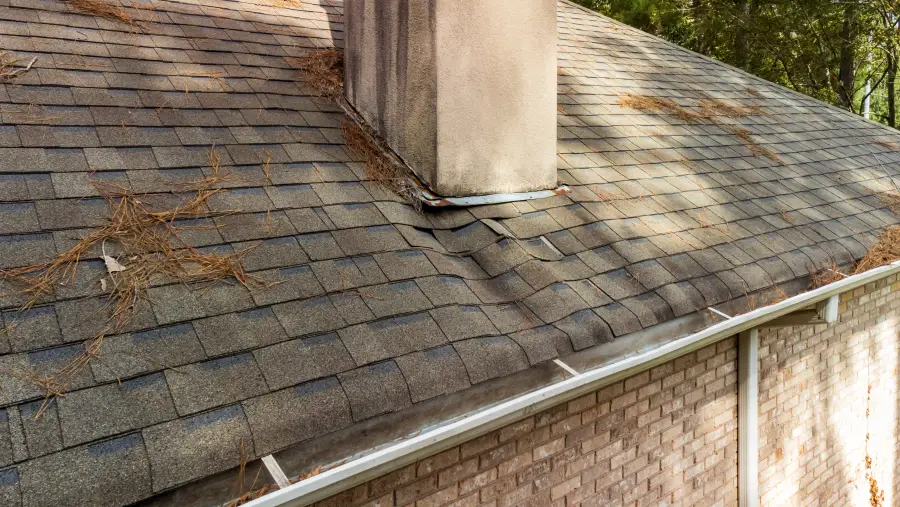 Close-up of roof shingles and chimney flashing vulnerable to water intrusion