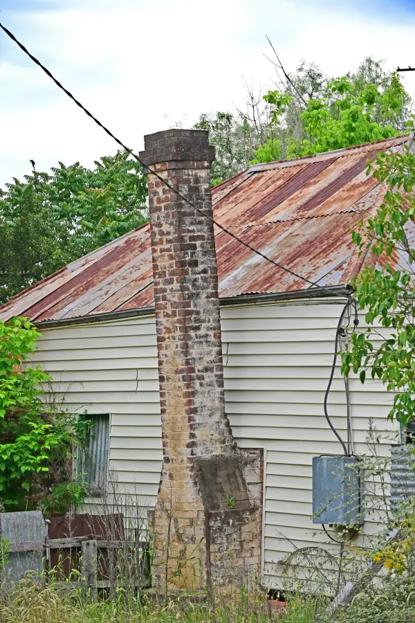 A severely leaning brick chimney pulling away from an older Kentucky home