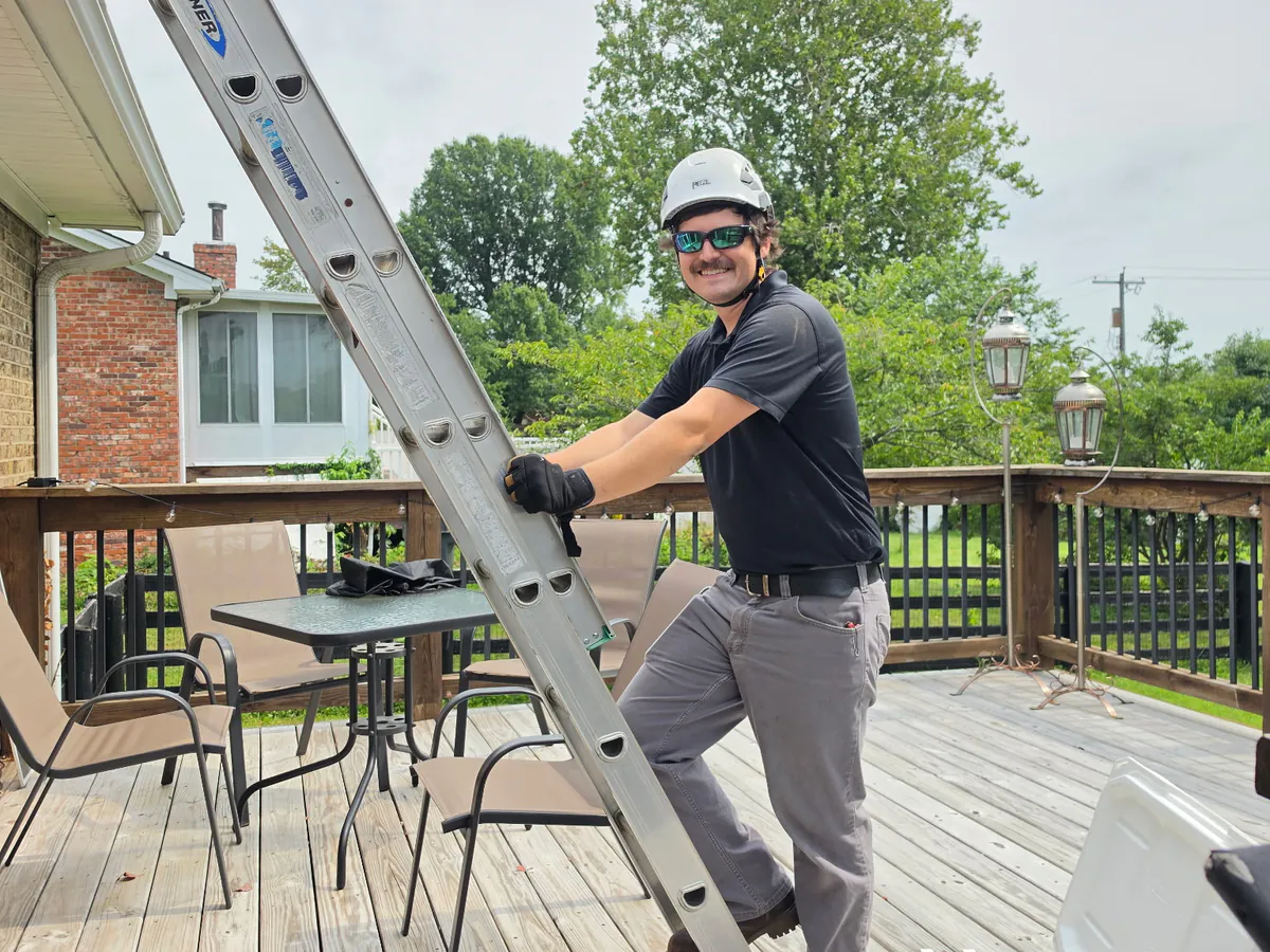Barnhill technician on a ladder heading up to inspect a chimney leak at a Lexington, KY home