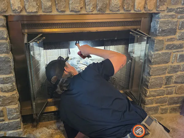 Barnhill technician checking a firebox with a flashlight during a chimney sweep and inspection