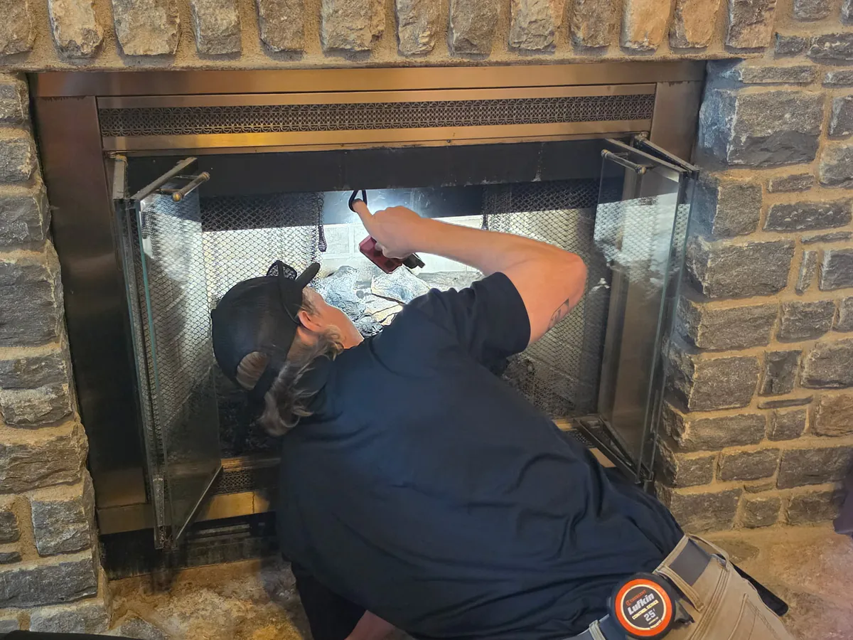 Barnhill technician checking the firebox with a flashlight during a chimney sweep and inspection in Lexington, KY